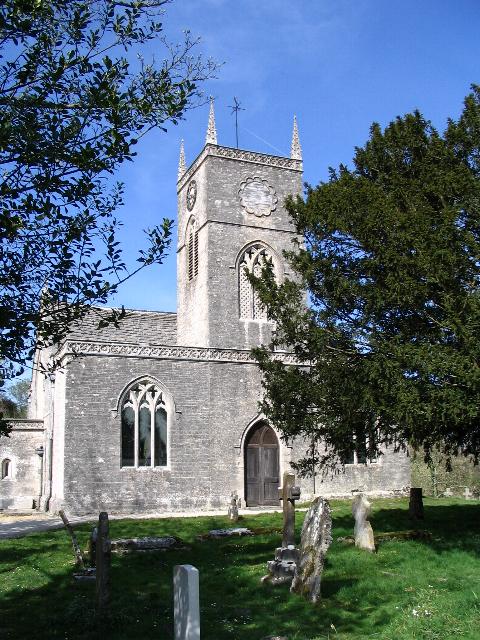The church tower framed by leafy trees, with gravestones in the foreground